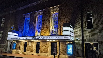 An image showing the Assembly Hall Theatre lit up in blue and yellow
